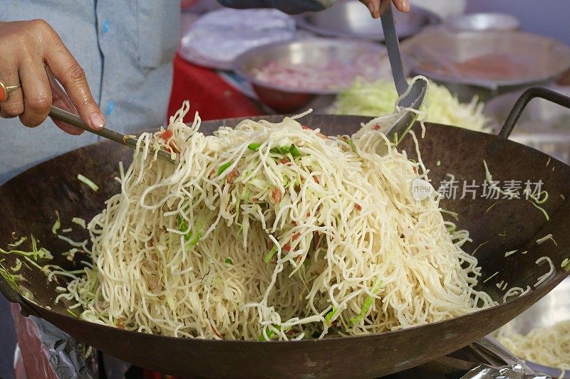 印度/中国街头食物在锅里烹饪，健康的新加坡面条/炒面与辣椒和洋葱一起炒，在煤气炉上烹饪